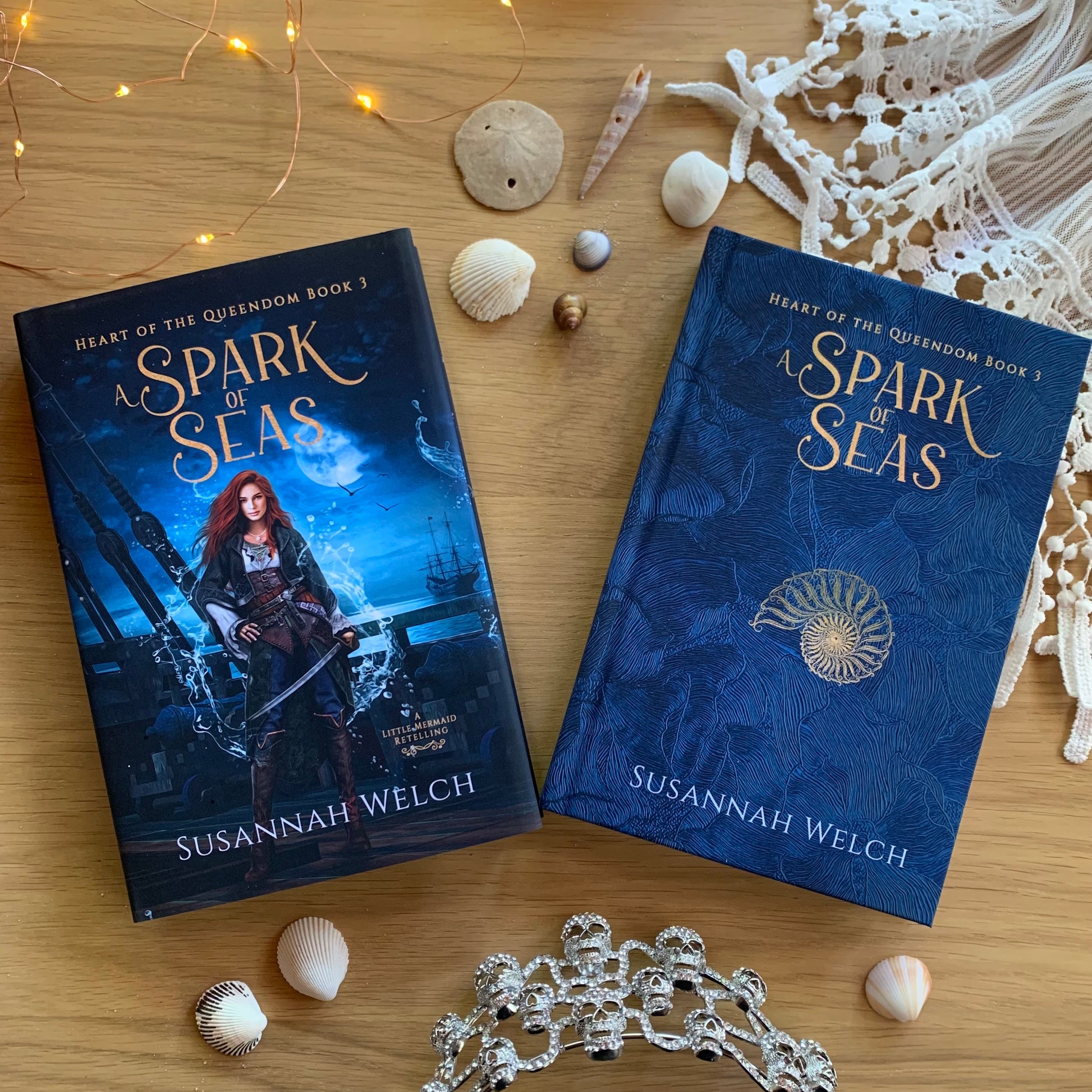 A Spark of Seas hardback with pirate woman on the book jacket - interior cover has seashell on a blue background